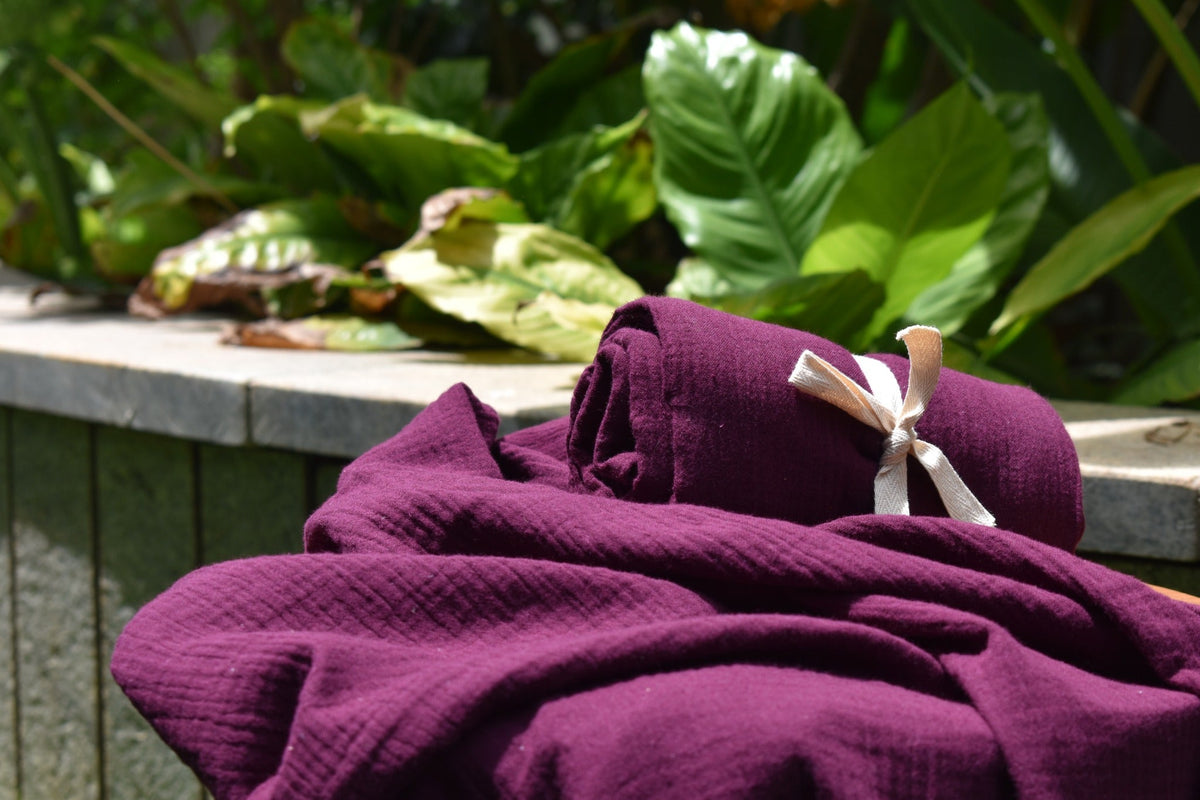 Purple cotton muslin towel tied with a cream ribbon, photographed outdoors
